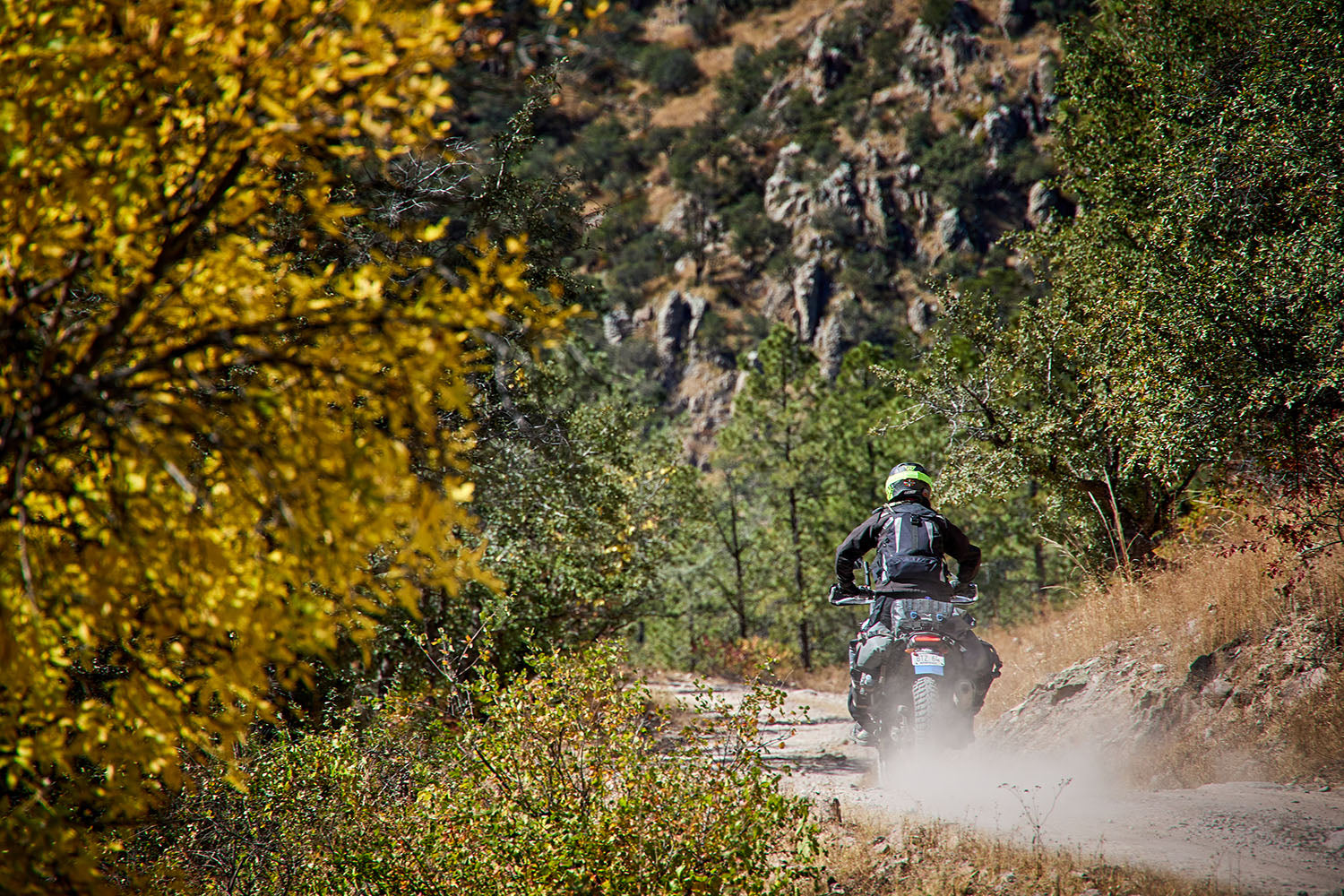 MOTORCYCLE RIDER CRUSING INTO THE DISTANCE ON A GRAVEL ROAD